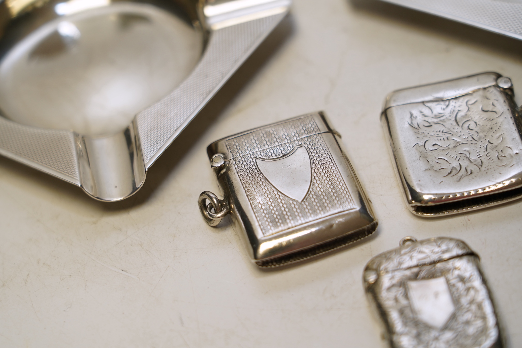 A pair of George V Asprey & Co silver ashtrays, 86mm and three assorted silver vesta cases. Condition - fair to poor.